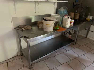 une cuisine équipée d'une table en inox et d'une étagère en métal