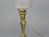 an antique brass table lamp with a frosted glass shade