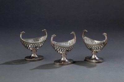 trois vases en argent empilés les uns sur les autres, posés sur une table
