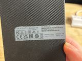 the back of a hand holding a black box with a sticker on it