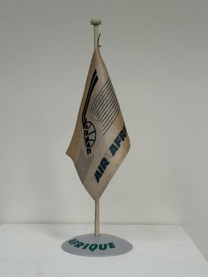 un petit drapeau posé sur un support, sur une surface blanche