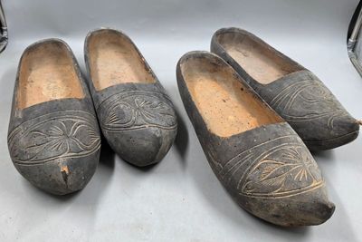 trois paires de vieilles chaussures en bois posées sur une surface blanche