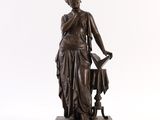 une statue antique en bronze représentant une femme tenant un arrosoir