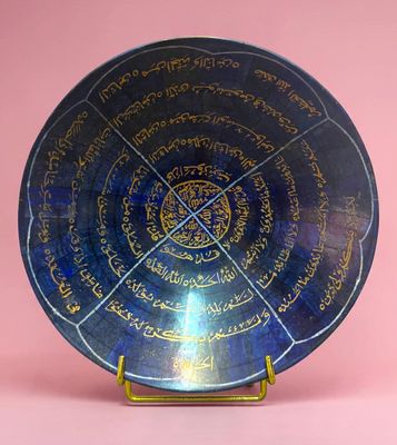 l'image d'une assiette bleue portant une inscription, posée sur un fond rose
