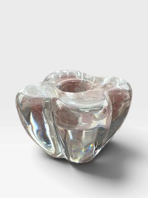 un bougeoir en verre transparent posé sur une surface blanche