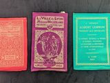 Trois livres sont alignés sur une table devant un fond noir.