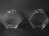 two clear glass hexagonal jars on a black background