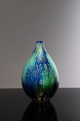 un vase bleu et vert posé sur une table noire
