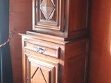 a wooden cabinet in the corner of a room with a window