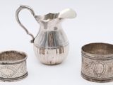 three pieces of silverware including a pitcher, cup, and saucer