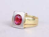 a close up of a gold and silver ring with a red stone