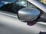 a side view mirror of a silver car with a mountain in the background