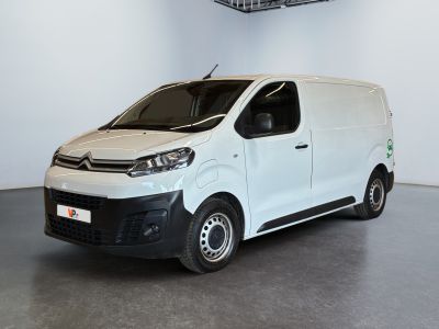 La camionnette blanche est garée dans une grande pièce équipée d'un ventilateur de plafond.