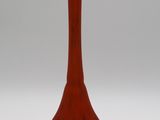 un vase rouge posé sur une surface blanche