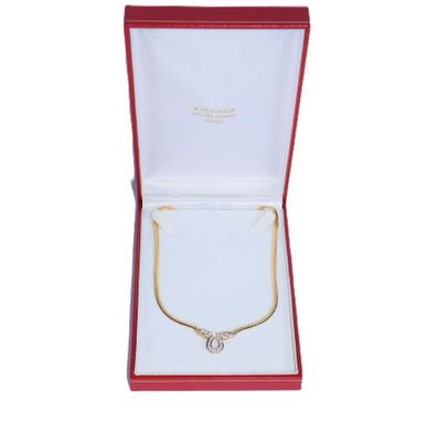 une boîte ouverte contenant un collier en or et un ruban rouge