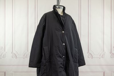 the black coat is hanging on a mannequin stand