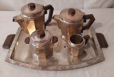 un plateau en argent sur lequel sont posées trois cafetières et une tasse