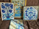 Trois œuvres d'art sont posées sur un lit recouvert d'une couverture marron