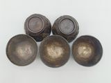 four antique metal bowls sitting on top of a white surface