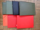 four different colored binders are lined up on a wooden floor