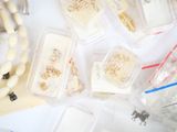many different types of beads in plastic containers on a table