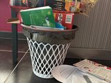 a trash can filled with books and papers on the floor