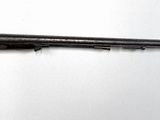 un fusil accroché au mur d'une pièce aux murs blancs