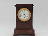 une petite horloge en bois avec un cadran blanc sur fond blanc
