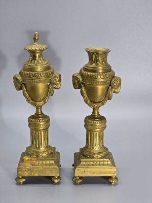 pair of antique brass urns on pedestals on grey background