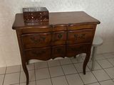 a small wooden chest of drawers in a bathroom with a urinal