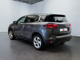 the rear of a grey car is parked in a garage