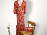 une image représentant un mannequin vêtu d'une robe rouge et assis sur une chaise en bois