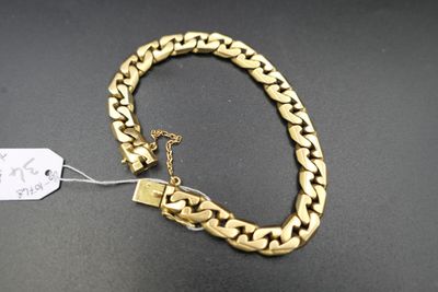 gros plan d'un bracelet en chaîne en or sur une surface noire