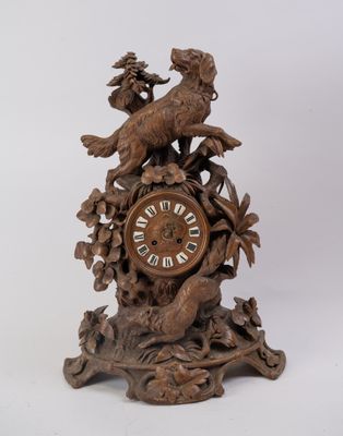 Importante pendule en bois sculpté à décor d'un chien devant…