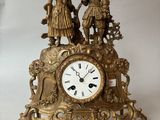 a gold clock with figures on it on a white surface