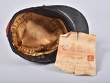 an old black hat with a tag on it sitting next to a piece of paper