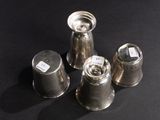 three silver pepper shakers sitting on top of a black table