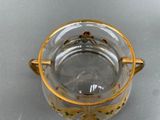 a glass container with a gold handle on a table