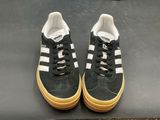 pair of black and white adidas sneakers with gum soles on a black surface