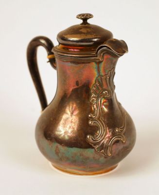 a small copper pitcher with a lid on a white surface