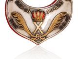 une image représentant une broche blanche et dorée ornée d'une couronne
