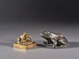 two silver and gold frog figurines sitting on top of each other
