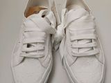 pair of white tennis shoes with bows on them on a white surface