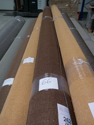 many rolls of fabric on a conveyor belt in a warehouse