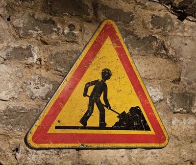 un panneau jaune et rouge sur lequel figure l'image d'un ouvrier du bâtiment