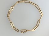 gros plan d'un bracelet en or sur une surface blanche