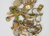 a pile of gold and silver jewelry on a white surface