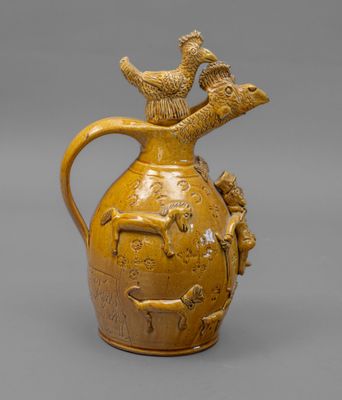 cruche émaillée jaune, ornée d'oiseaux sur le dessus, sur un fond gris