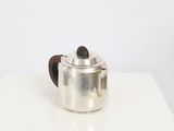 a silver tea pot with a wooden handle on a white table