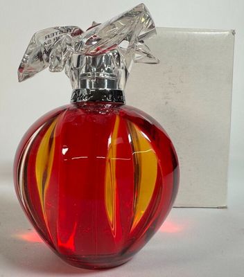 un flacon de parfum en verre rouge surmonté d'un oiseau